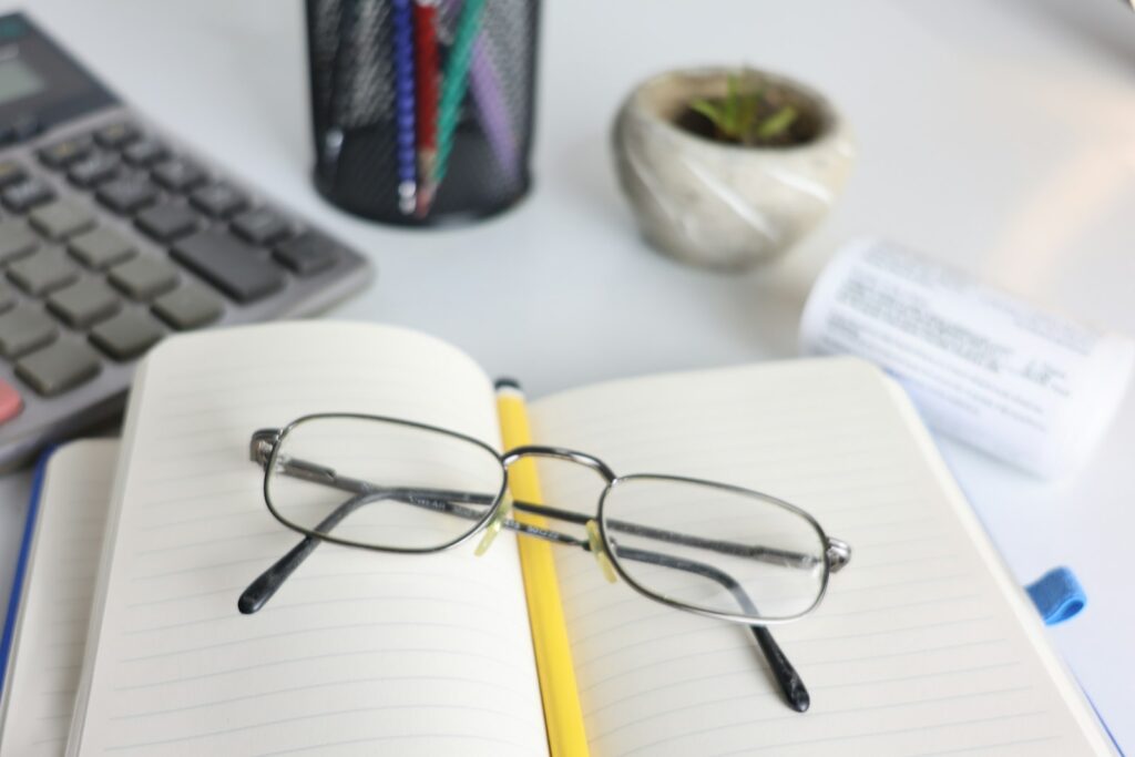 Open notebook with glasses, pencil and calculator on a desk